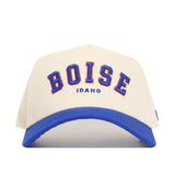 The No Rivals Boise Hometown Hat is a white snapback with a structured fit, bold blue brim, and "BOISE" in large blue and red letters above "Idaho" in smaller blue, all on cotton fabric.