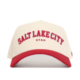 The No Rivals Salt Lake City Hometown Hat is a beige cotton baseball cap with a red brim and "Salt Lake City Utah" embroidered in red on the front, providing a structured fit and classic style.