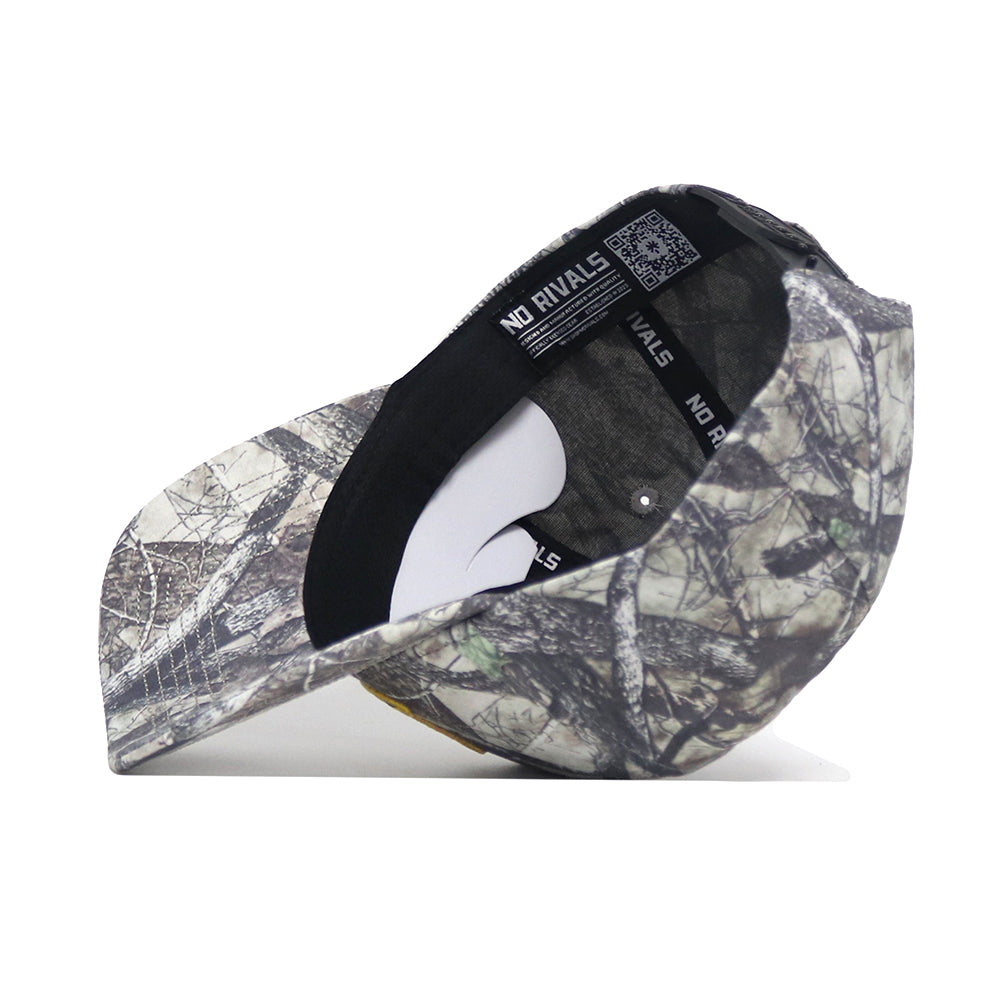 The Oregon Outland Hat by No Rivals is shown upside down, displaying its black NO RIVALS sweatband and a white tag. Made from high quality cotton, the cap features a forest camouflage pattern.
