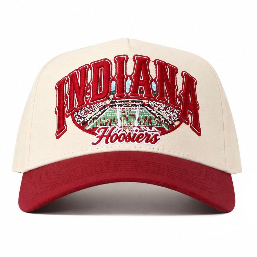 The Indiana Hoosiers Stadium Hat by No Rivals features a cream and red design with an embroidered “Indiana” and “Hoosiers” logo above and below a detailed football stadium graphic, and is finished with a classic snapback closure for the perfect gameday fit.