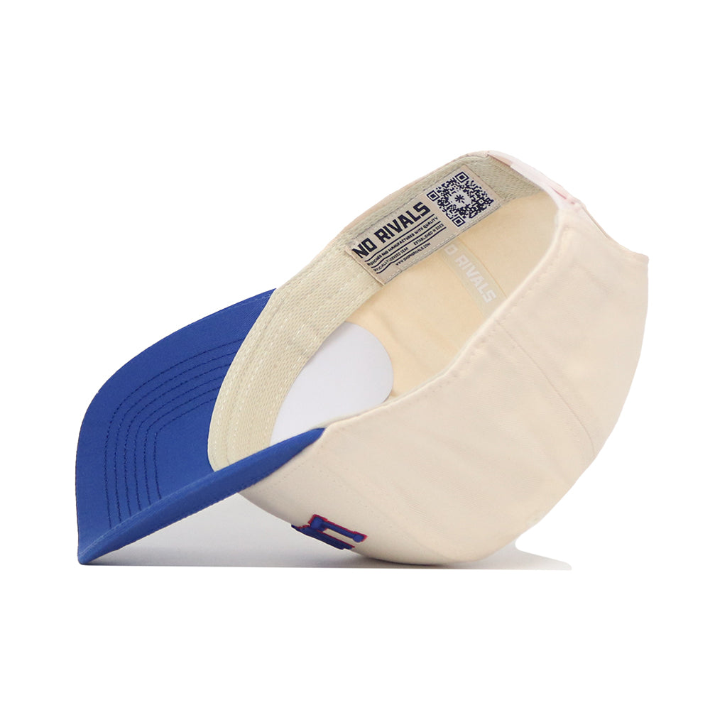 The Lawrence Hometown Hat by No Rivals is a cream-colored, structured fit cap with a blue brim, shown upside down to display its quality cotton inner labels, detailed stitching, a NO RIVALS tag, and an inside QR code.