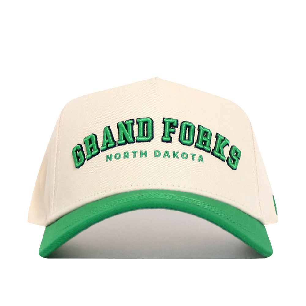 The No Rivals Grand Forks Hometown Hat is a cream snapback with a green brim, structured fit, and quality cotton. “GRAND FORKS” is embroidered in green with “NORTH DAKOTA” below on the front.