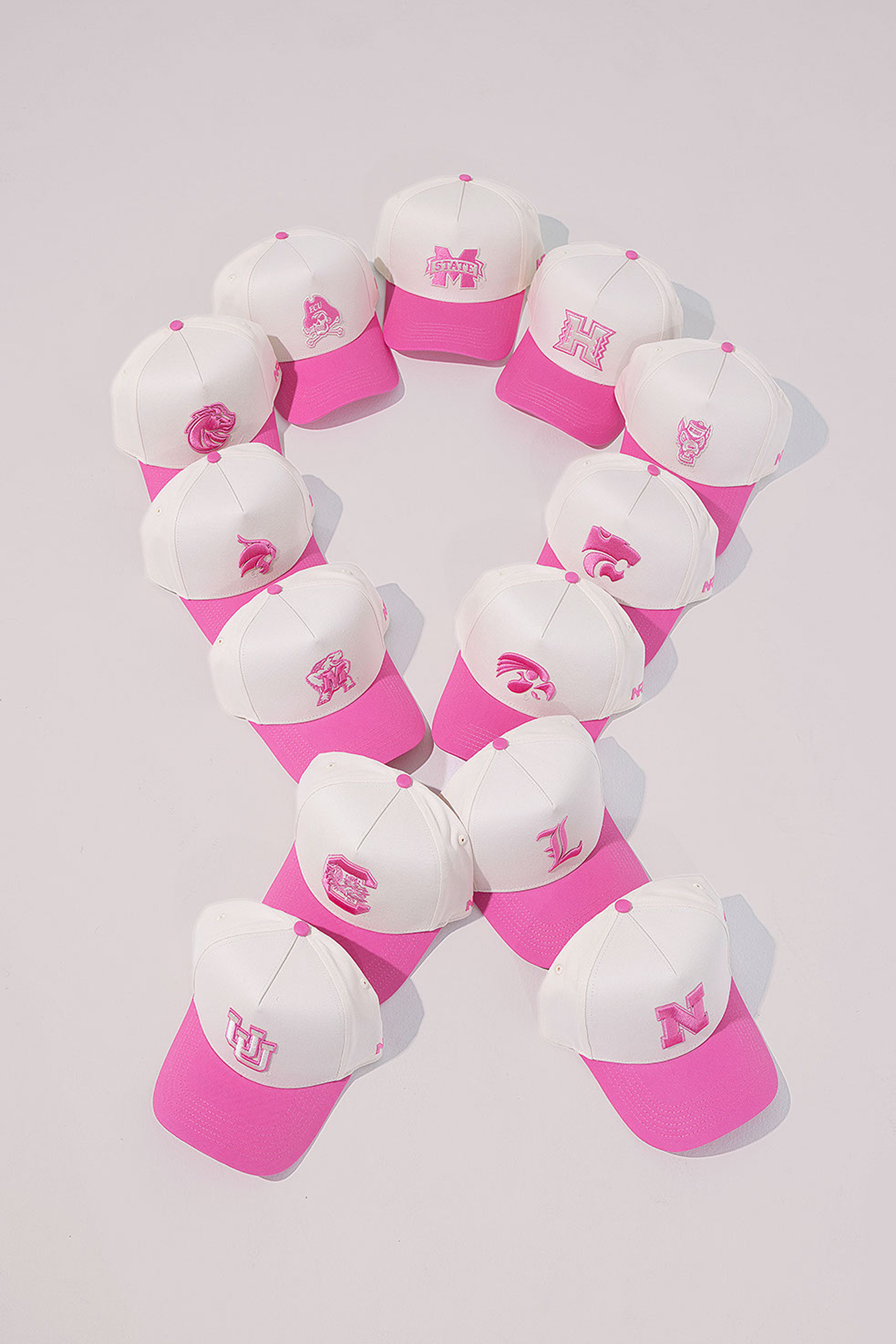 Pattern of pink and white caps with various logos on a white background