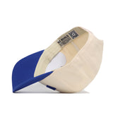 The Omaha Hometown Hat by No Rivals is shown upside down, displaying its inside tags and adjustable strap. This snapback hat features a blue bill with beige panels for a comfortable, stylish look.