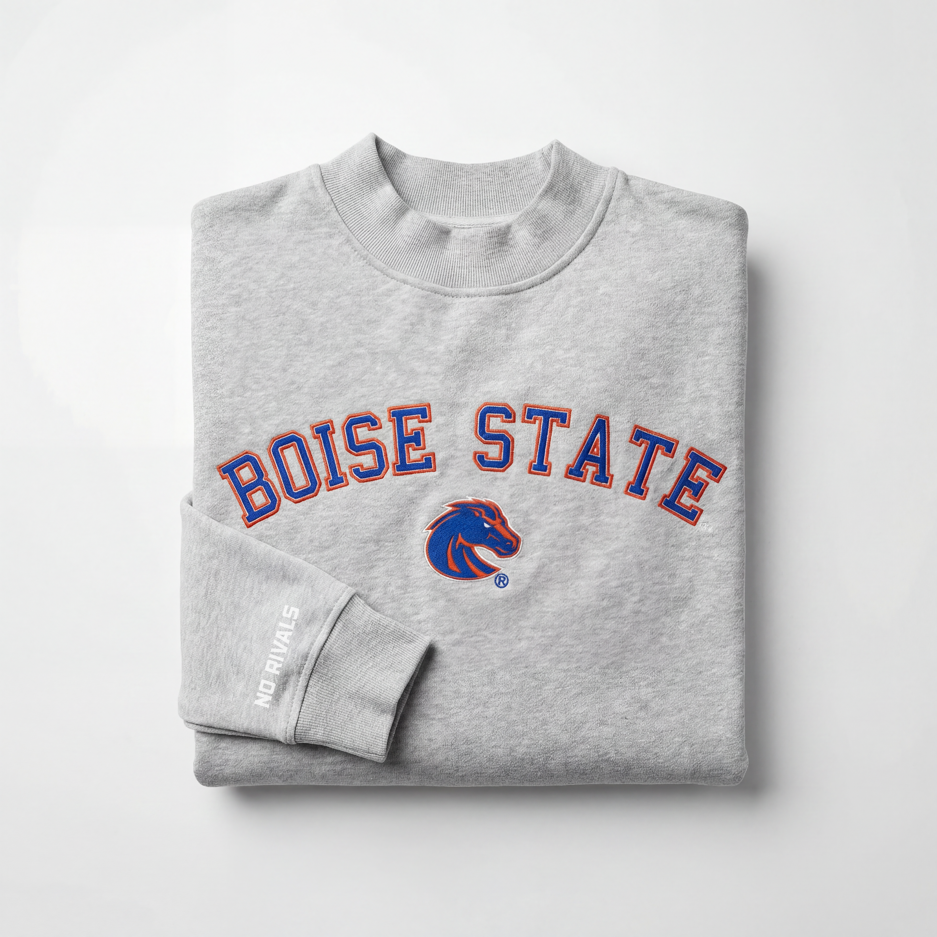 The Boise State Mock Neck by No Rivals is a folded gray sweatshirt with a mock neck, featuring blue and orange BOISE STATE lettering and a Bronco logo, plus “NO RIVALS” in white on the sleeve. Displayed against a plain white background.