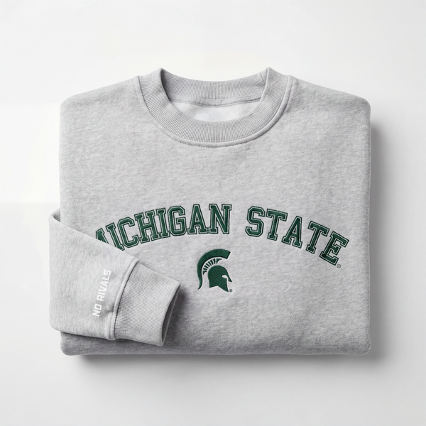 The Michigan State Mock Neck by No Rivals is a folded gray heavyweight cotton sweatshirt featuring "MICHIGAN STATE" and a green Spartan helmet on the front, plus "NO RIVALS" in white near the cuff, set on a plain white background.