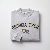 The Georgia Tech Mock Neck by No Rivals is a heavyweight gray, oversized sweatshirt with GEORGIA TECH and the GT logo in yellow and black on the front, plus "NO RIVALS" text on the sleeve, shown folded on a plain white background.