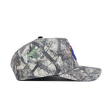 The Boise State Outland Hat by No Rivals is a camouflage snapback cap made of high-quality cotton, seen in side profile on a white background. A blue circular patch with red trim accents the structured front for a classic look.