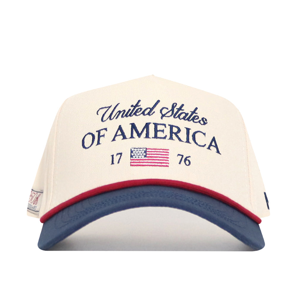 The No Rivals USA Classic Americana Hat is a beige snapback featuring "United States OF AMERICA 1776" in blue, a small U.S. flag, and a blue bill with red trim, made from high-quality cotton for a structured fit.