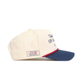 The No Rivals USA Classic Americana Hat is a cream baseball cap with a blue brim, red accent, and "250th Anniversary" side patch. Made of high-quality cotton, this structured snapback features partially visible front text.
