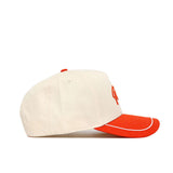 The No Rivals OSU Pokes ALOYO Hat (B2B) is a cream cotton baseball cap with an orange brim, piping, and top button. Seen from the side on a white background, it features a structured fit and a partially visible embroidered front design.