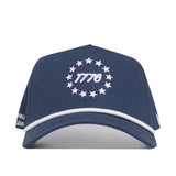 The No Rivals USA 1776 Americana Hat is a navy blue cotton snapback with white trim, featuring "1776" and a circle of white stars embroidered on the front for a comfortable, adjustable fit.