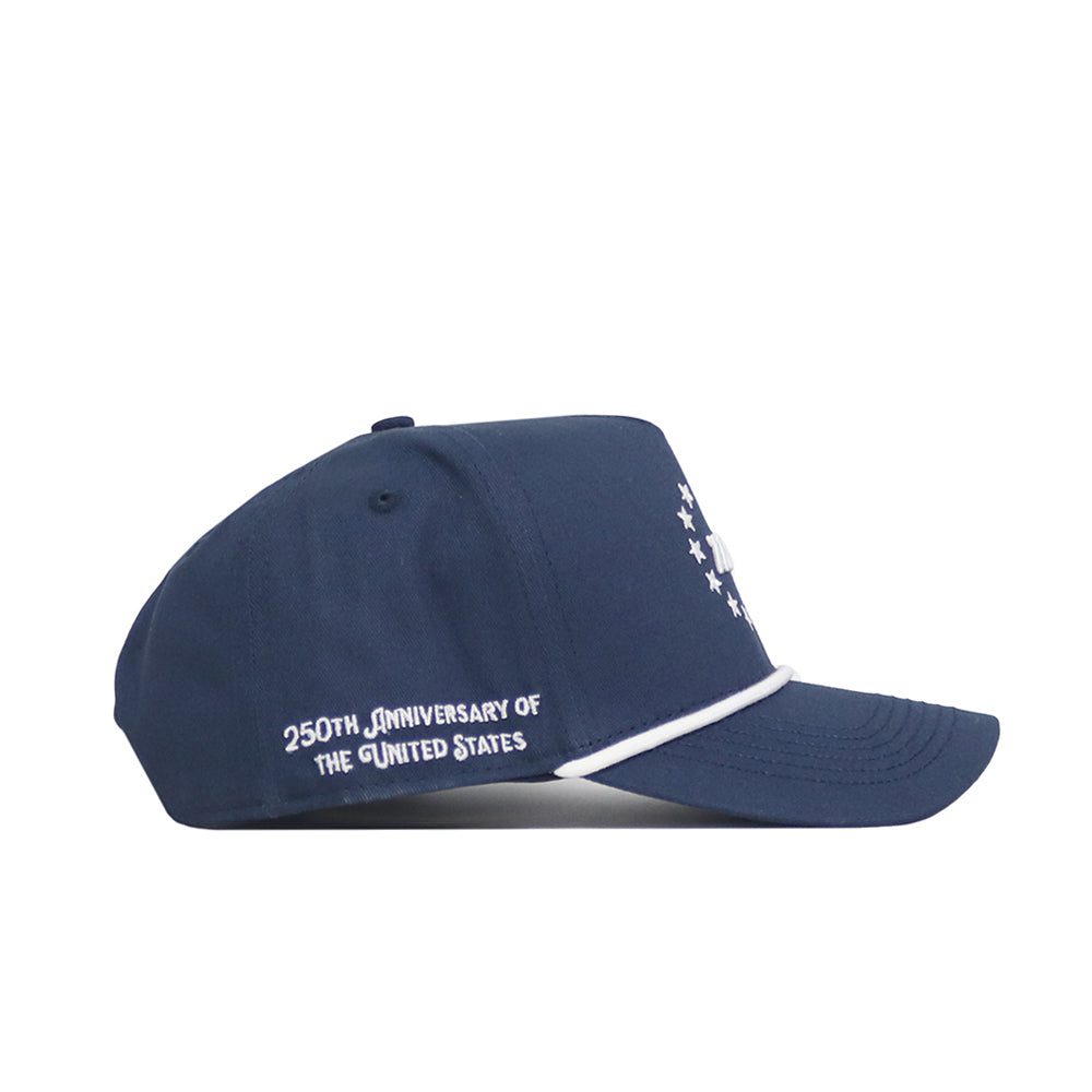 The No Rivals USA 1776 Americana Hat is a navy snapback made from cotton, with white front stars, white piping, and "250th Anniversary of the United States" stitched on the side. Structured fit for style and comfort.