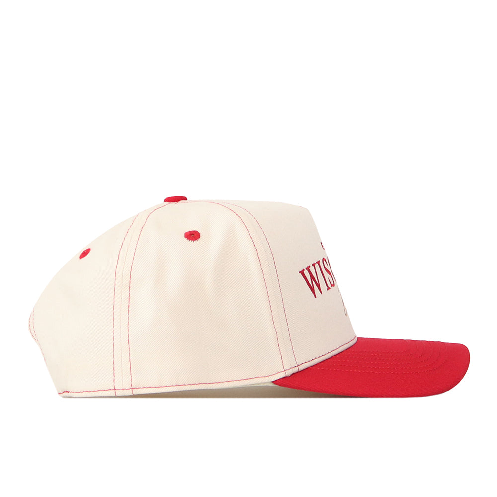 Showcased in a side profile view against a white background, the No Rivals Wisconsin Badgers Vintage Hat features a cream-colored design with red stitching, red ventilation holes, and a bold red brim. Finished with an embroidered logo and classic snap back closure, this cap is perfect for elevating your gameday look.