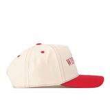 Showcased in a side profile view against a white background, the No Rivals Wisconsin Badgers Vintage Hat features a cream-colored design with red stitching, red ventilation holes, and a bold red brim. Finished with an embroidered logo and classic snap back closure, this cap is perfect for elevating your gameday look.