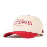 The Wisconsin Badgers Vintage Hat by No Rivals is a beige and red baseball cap featuring a bold, embroidered Wisconsin Badgers logo with “EST 1848” in striking red and gold on the front. It sports a vibrant red bill, classic sporty detailing, and an adjustable snap back closure for the ideal gameday fit.