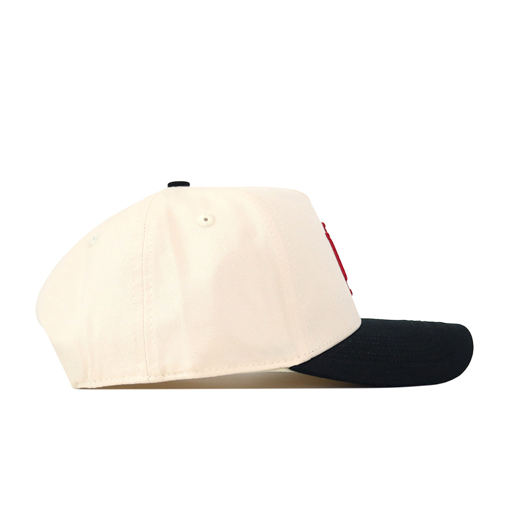 The Indiana Hoosiers Halftime Hat by No Rivals is a cream-colored baseball cap with a black brim, pictured from the side. It features two small ventilation holes on the side panel and an embroidered Indiana Hoosiers logo for a classic gameday fit.