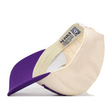The LSU Tigers Stride Hat by No Rivals is pictured upside down, showcasing its cream and purple colorway, interior details, care tag, and a QR code label on the inner band. Made from high-quality cotton, this snapback cap offers a structured fit for lasting comfort and style.