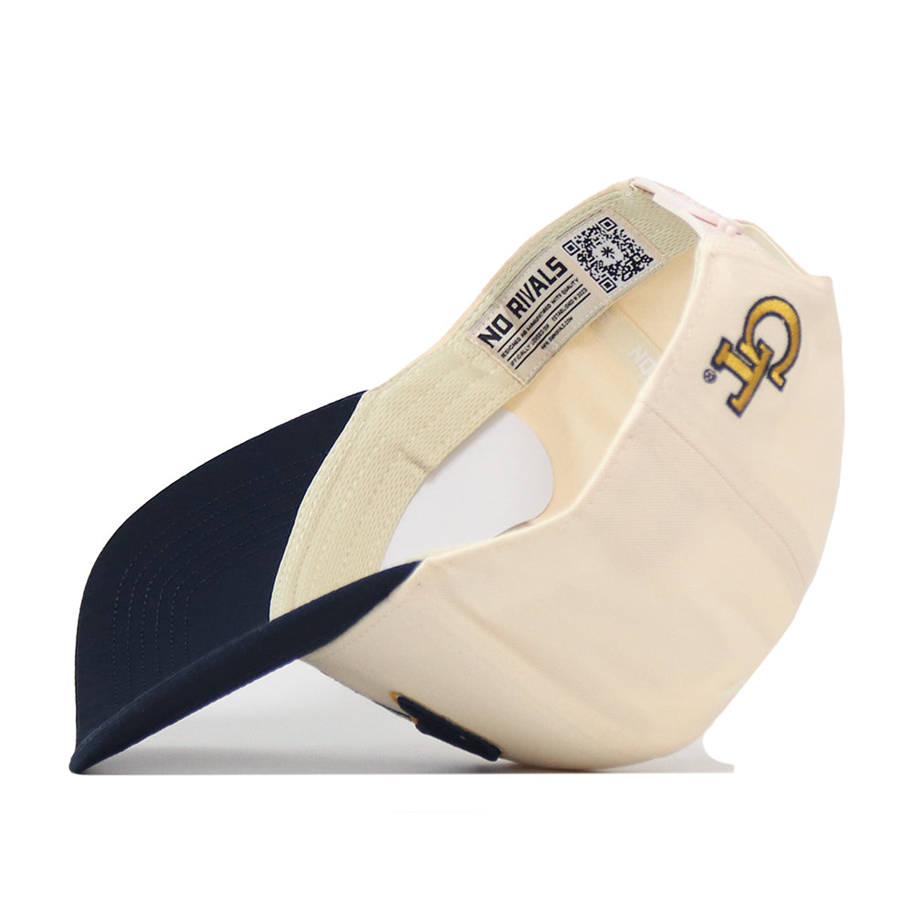 The No Rivals Georgia Tech Yellow Jackets Stadium Hat is shown flipped upside down, revealing its interior label and a finely stitched GT embroidered logo on the exterior—a classic cream and navy baseball cap with an adjustable snapback for the perfect gameday look.
