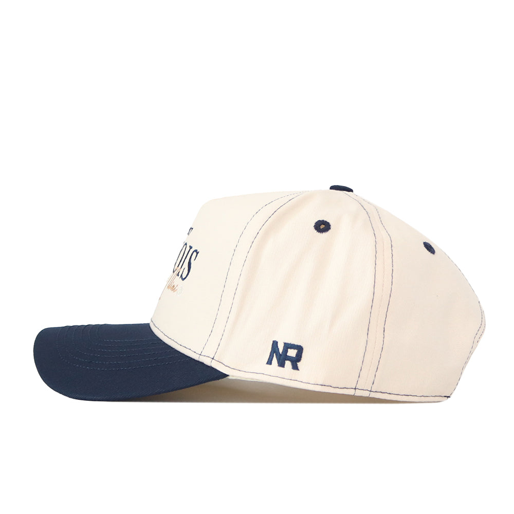 The Illinois Fighting Illini Vintage Hat by No Rivals is a cream-colored baseball cap crafted from high-quality cotton, featuring a navy blue bill and a small navy blue NR logo on the side. This officially licensed snapback combines comfort with timeless style.