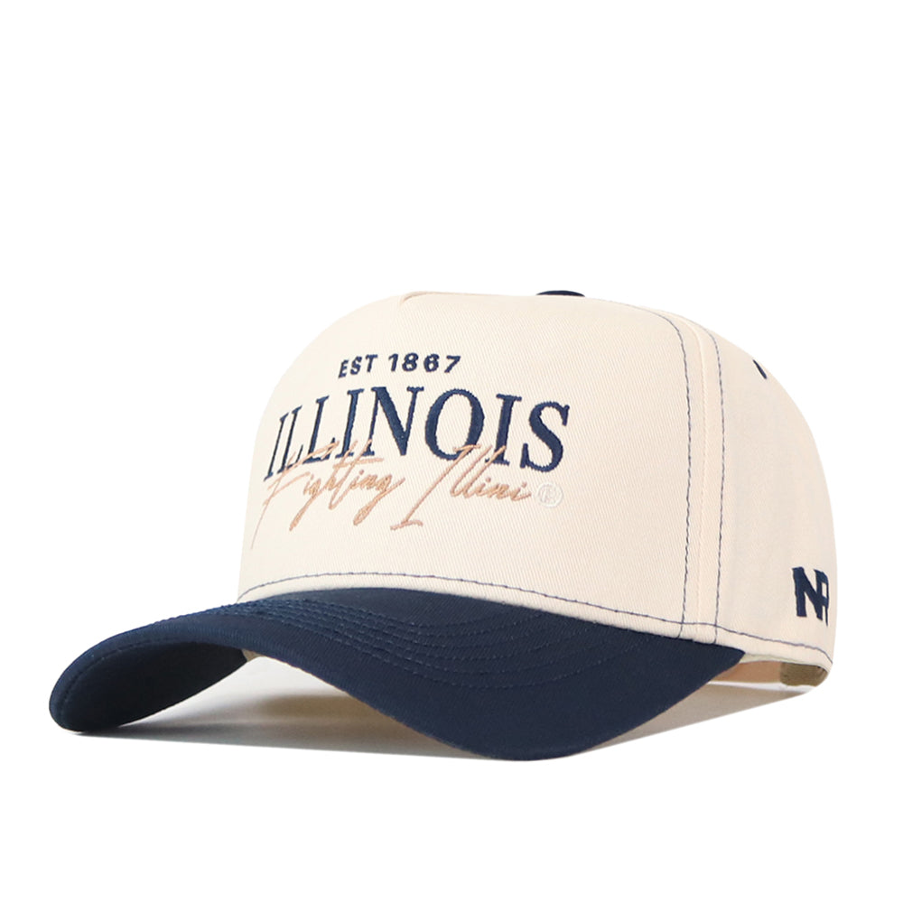 The Illinois Fighting Illini Vintage Hat by No Rivals is a cream and navy baseball cap crafted from high-quality cotton, featuring “EST 1867 ILLINOIS Fighting Illini” embroidered on the front and the No Rivals logo on the side. This officially licensed snapback hat provides both comfort and style for true fans.