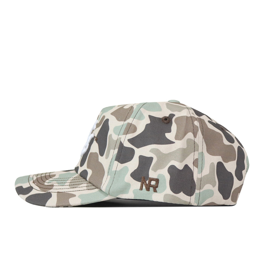 Introducing the Montana State Script Huntsman Hat by No Rivals—a 5-panel baseball cap featuring classic green, grey, and brown camouflage patterns. The hat showcases “NR” embroidered in brown on the side and is finished with a convenient snap back closure for an adjustable fit.
