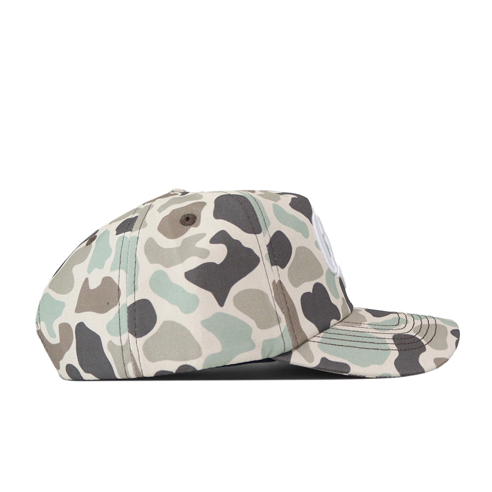The No Rivals Montana State Script Huntsman Hat is a 5-panel baseball cap featuring a green, gray, and beige duck camo pattern with a classic snapback closure, shown in a side view against a white background.