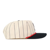The No Rivals Texas Tech Pinstripe Hat is a cream-colored baseball cap with thin black vertical stripes, a red trim above the brim, and a black brim, pictured from the side. Designed with an unstructured fit for casual style and comfort, this hat also features snapback adjustment to ensure one size fits most.