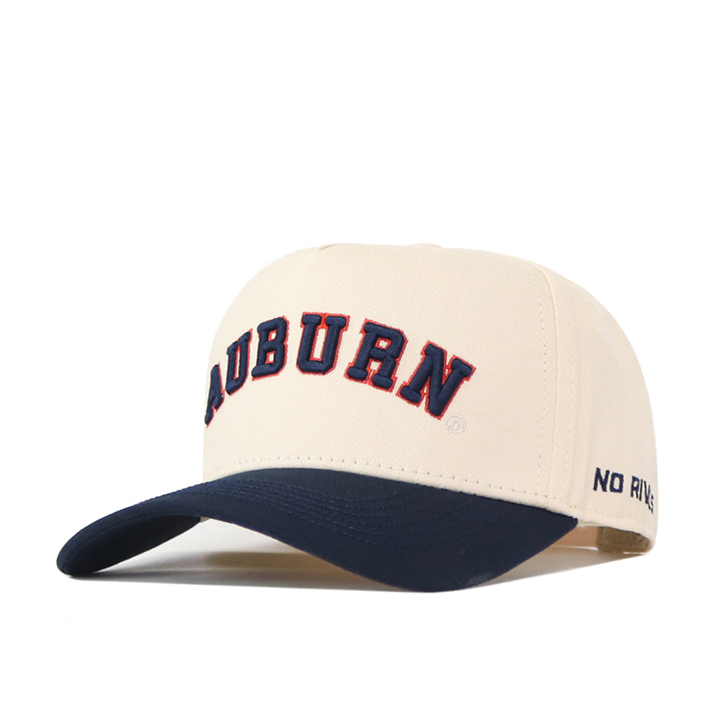 Introducing the Right Side Up Auburn Hat - Classic Colors by No Rivals: This beige snapback features “AUBURN” embroidered in bold navy and orange letters on the front, a navy blue bill, and an embroidered logo. “NO RIV” is stitched in blue on the side, making this hat the perfect addition to your gameday outfit.