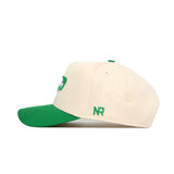 The North Dakota Logo Patch Hat by No Rivals is a cream baseball cap with a green brim, button, and side NR embroidery—offering structured fit, comfort, and style for golf or everyday wear.