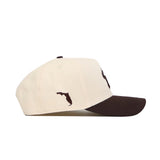 The No Rivals USF Espresso Hat is a cream baseball cap with a dark brown brim, made from high-quality cotton. It features an embroidered brown Florida silhouette on the side and offers comfort and style with its snapback design.