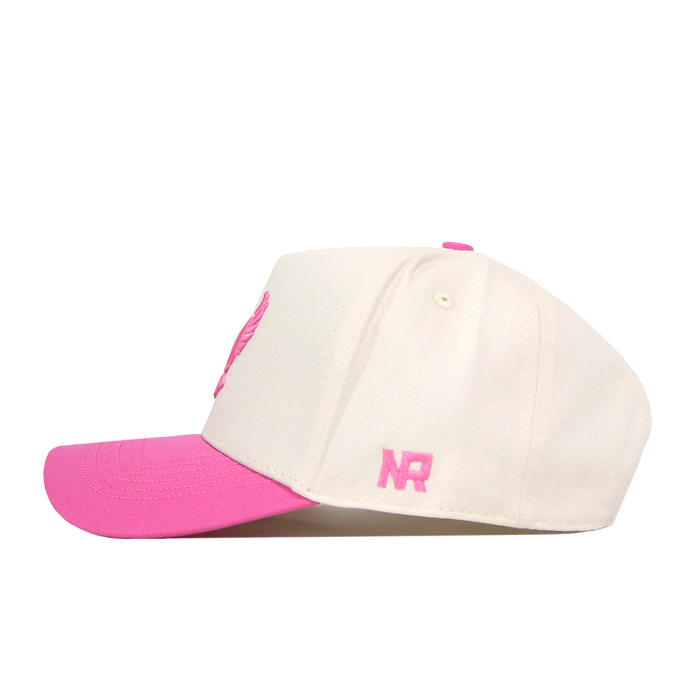 The EWU Pink Out Hat by No Rivals is a cream-colored baseball cap with a pink bill and pink embroidered details, including “NR” on the side. Made from performance fabric, the hat showcases an embroidered logo and is displayed in a side view against a white background.