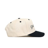 The No Rivals Golf Dept. Hat - Classic Black features a cream-colored cotton build, black brim, ventilation eyelets, and a partially visible black embroidered logo on the front. Shown from the side profile.