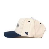 A vintage Ole Miss Rebels hat by No Rivals, this cap features a cream-colored crown with a navy blue brim and matching stitched accents. The side is embroidered with the initials NR and it includes an adjustable snap back closure—shown here in a side view, it’s the perfect finishing touch for your gameday ensemble.