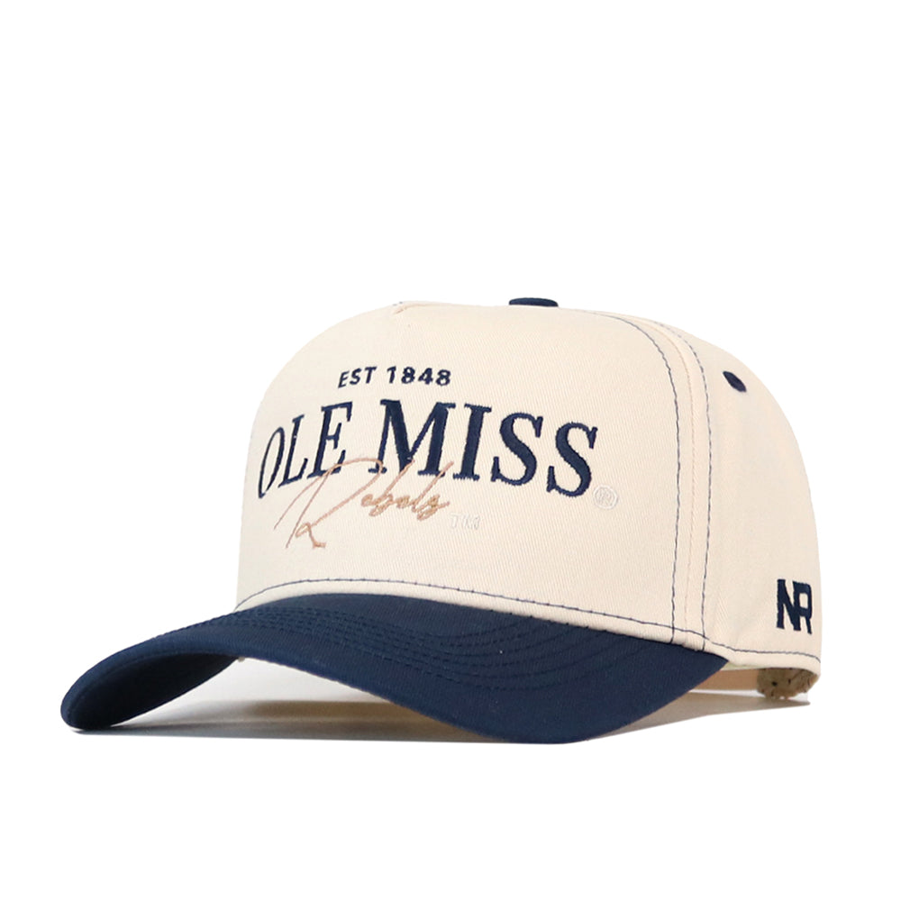 Introducing the Ole Miss Rebels Vintage Hat – Navy by No Rivals, an officially licensed snapback cap in classic cream and navy. Featuring “EST 1848 OLE MISS Rebels” embroidered on the front and the No Rivals “NR” logo on the side, this hat is designed with a left-angled brim to perfectly complete your ultimate gameday look.