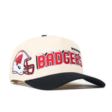 The Wisconsin Alma Mater Hat by No Rivals is a beige and black snapback made from high-quality cotton. It showcases a red football helmet and “BADGERS” in bold red lettering, with “WISCONSIN” embroidered above. Embroidered logos on the front and side complete its standout style.