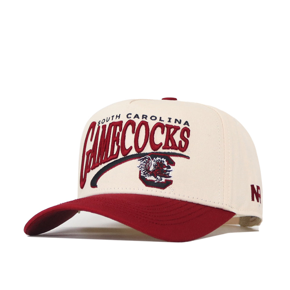 Show your team pride with the South Carolina Gamecocks Stride Hat by No Rivals. This cream and red snapback cap features the iconic gamecock logo embroidered on the front, “NC” stitched on the side, and a bold red brim. Made from high-quality cotton for superior comfort, it offers a structured fit perfect for fans.