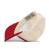 The Oklahoma Sooners Stride Hat by No Rivals is shown upside down, displaying its red and beige snapback design, inner lining, structured fit stitching, and a label with text and a QR code inside the cotton material.