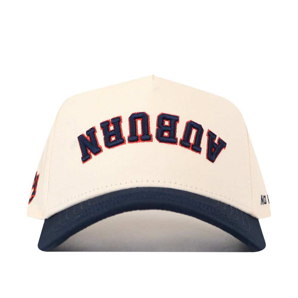 Check out the Auburn Tigers | Upside Down Auburn Hat - Classic Colors by No Rivals: This unique snapback cap features a white crown with a navy blue brim. The word “AUBURN” is embroidered upside down on the front in blue, outlined in orange, making it a standout piece for fans.