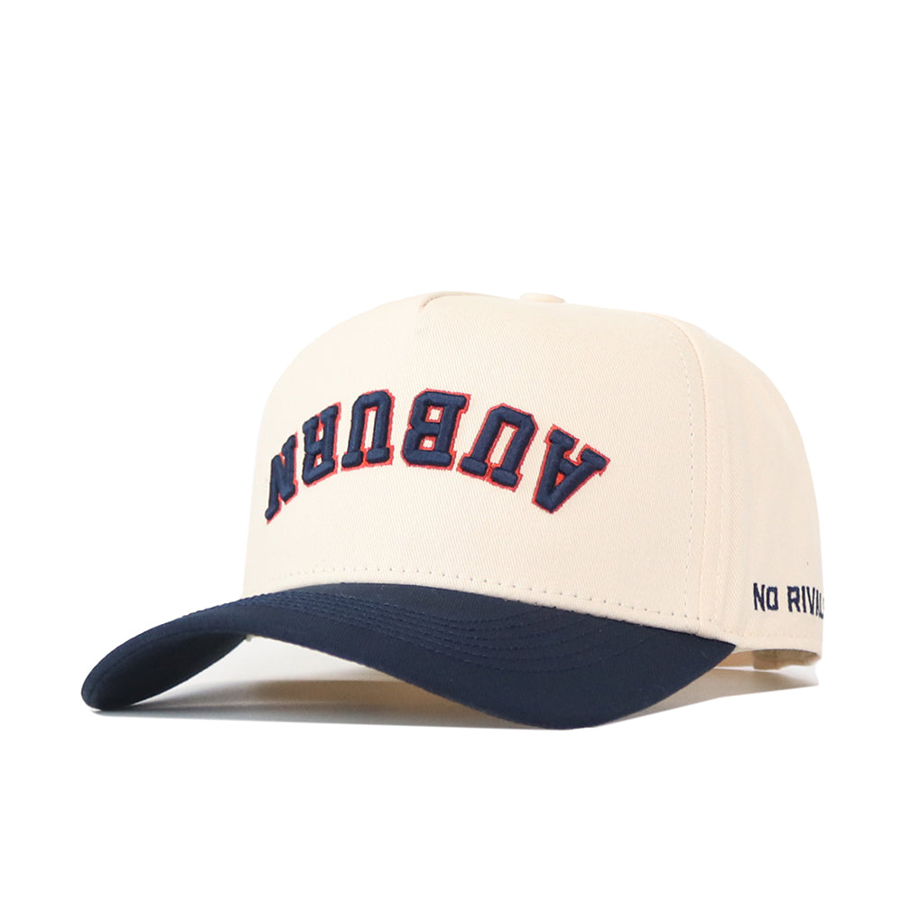 Sure! Here’s a rewritten sentence using the given product data: The Auburn Tigers | Upside Down Auburn Hat - Classic Colors by No Rivals features a beige crown with “AUBURN” displayed in bold navy and orange letters on the front and “NO RIVAL” embroidered in navy on the side. The dark blue brim adds a timeless touch, while an adjustable snapback provides a comfortable fit.