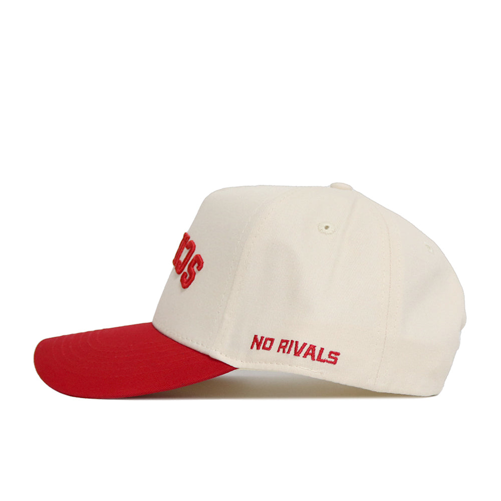 The Upside Down Scheels Hat is a cream cotton baseball cap with a red brim, featuring "NO RIVALS" embroidered in red on the side and an adjustable snapback closure for a perfect fit.