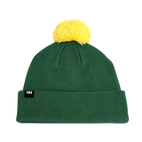 The North Dakota State Bison Logo Beanie by No Rivals is a green knit hat featuring a folded brim, a large yellow pom-pom on top, and crafted from a high-quality cotton blend for exceptional comfort. A small black tag with white “NR” lettering is attached to the brim.