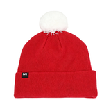 The No Rivals Wisconsin Badger Logo Beanie is a red knit hat made from a high-quality cotton blend. It features a white pom-pom on top and a small black patch with white “NR” letters embroidered on the folded brim, shown against a white background.