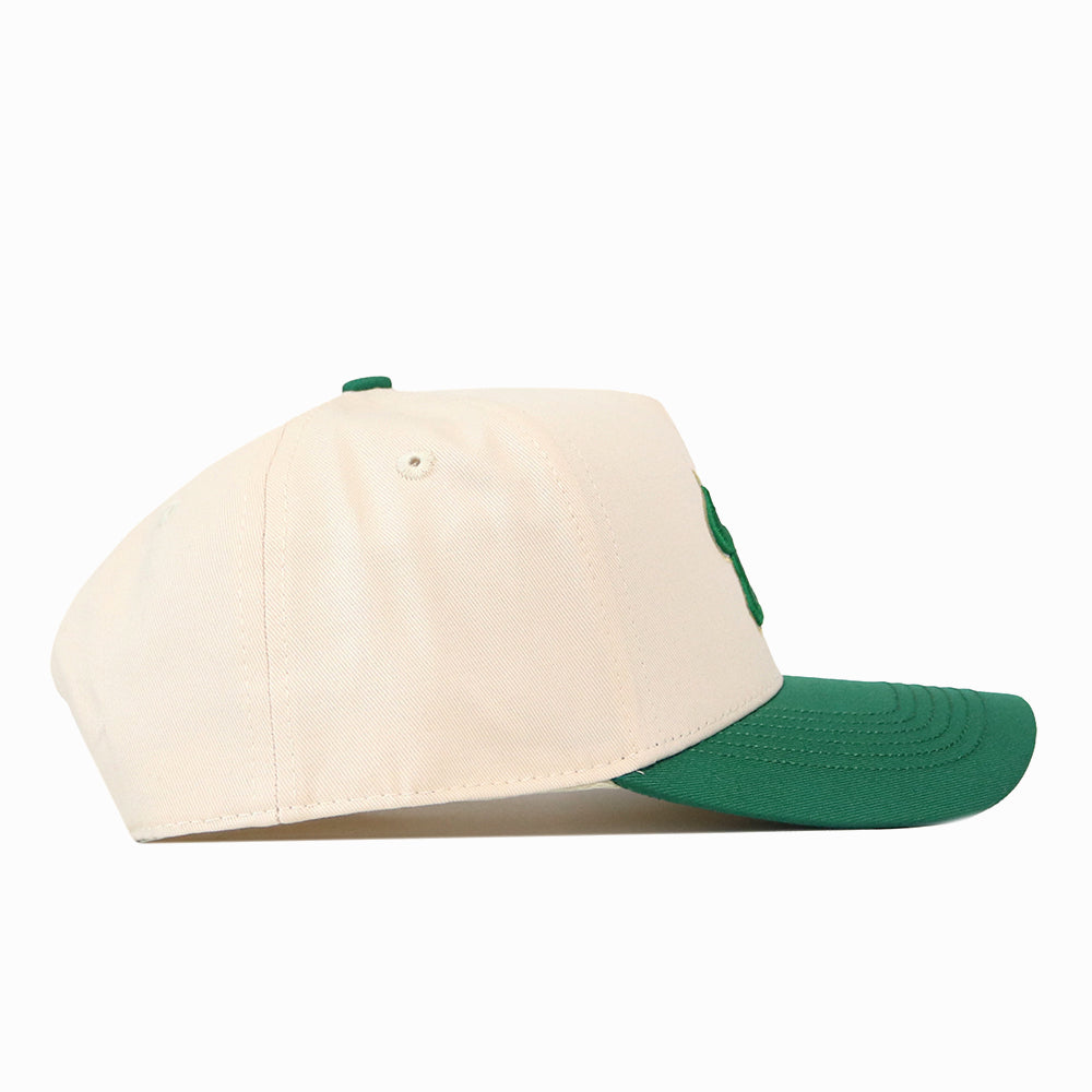Side view of a cream USF Halftime Hat snap back baseball cap with a green visor and green embroidered logos.
