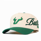 No Rivals USF Halftime Hat: an off-white snapback with a green brim, featuring a green U logo on the front and Bulls embroidered in green cursive on the side.