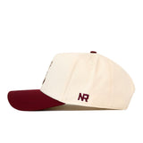 Side profile of a cream-colored Texas A&M Bear Hat - 5 Panel Structured with a maroon brim and embroidered graphics on the side.