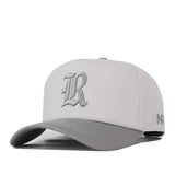 A light gray Rice Graphite Hat by No Rivals, featuring a dark gray brim and an Old English style letter R embroidered on the front.