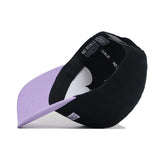 The ECU Dugout Collection Hat - Powder Purple by No Rivals is pictured upside down, revealing its lavender brim underside, inner lining, and "NO RIVALS" branding on the inside band. Crafted from high-quality cotton.