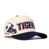 The Auburn Alma Mater Hat by No Rivals is a cream and navy snapback featuring a football helmet graphic and bold TIGERS embroidery on the side—perfect for finishing off your ultimate gameday look.