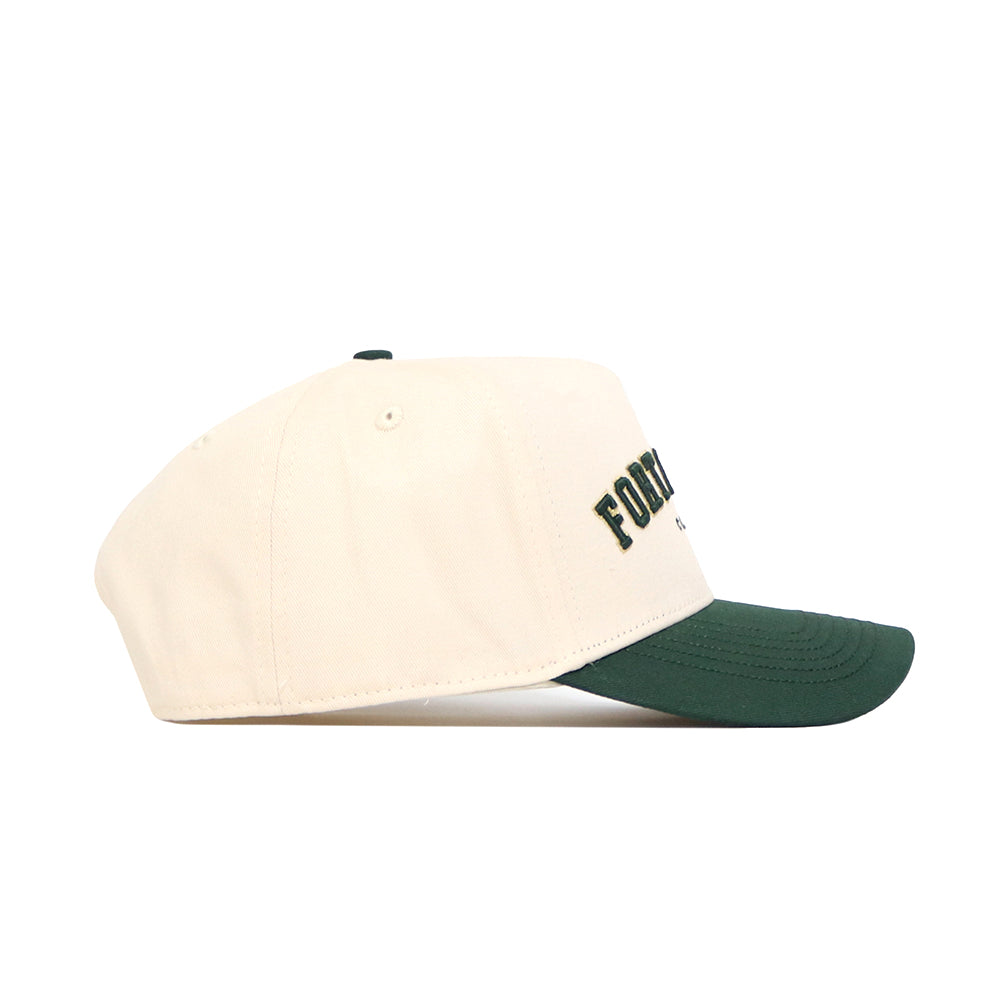 The No Rivals Fort Collins Hometown Hat is a cream snapback cap with a dark green curved brim, structured fit, and partially visible black text on the front. Made of high-quality cotton, it's shown from the side.